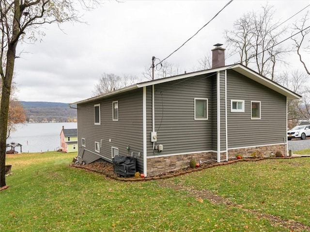 view of home's exterior featuring a lawn and a water view