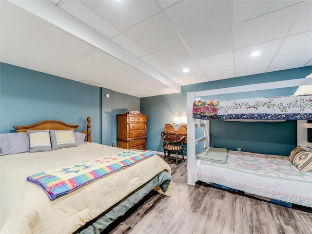 bedroom with hardwood / wood-style floors and a paneled ceiling