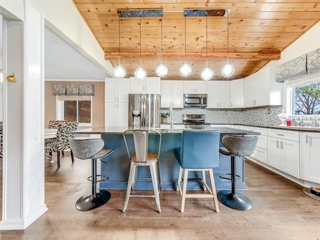 kitchen featuring decorative light fixtures, dark stone countertops, wooden ceiling, and appliances with stainless steel finishes