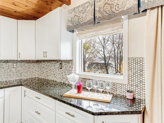 kitchen with backsplash, dark stone countertops, white cabinets, and wooden ceiling