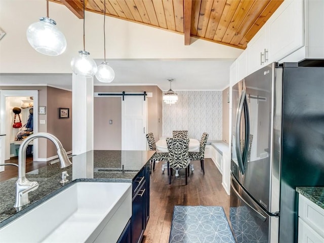 kitchen featuring stainless steel refrigerator, sink, pendant lighting, and a barn door