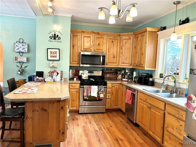 kitchen with a breakfast bar, sink, stainless steel appliances, and decorative light fixtures