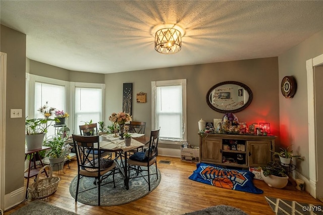 dining space with light hardwood / wood-style flooring and a textured ceiling