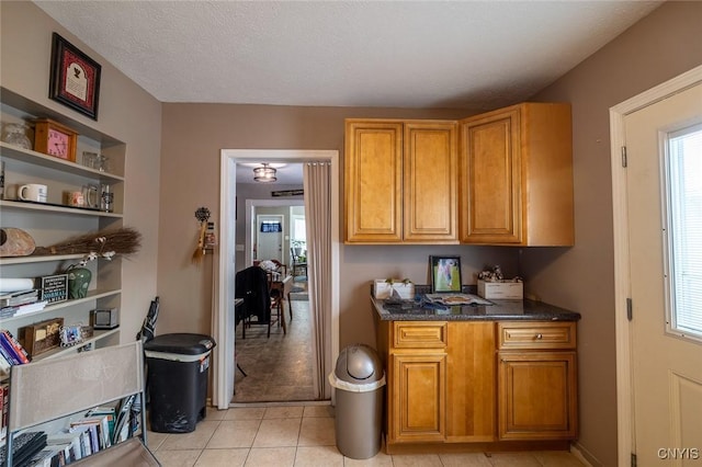 kitchen featuring light tile patterned flooring, a textured ceiling, and dark stone counters