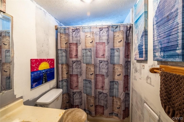 bathroom featuring shower / bath combination with curtain, toilet, and a textured ceiling