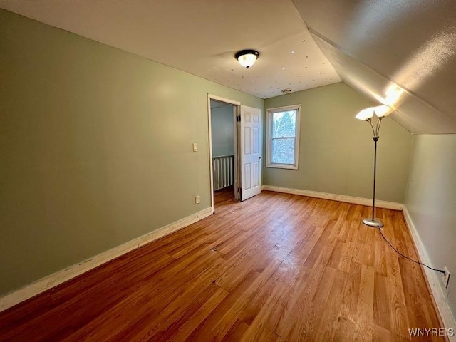 additional living space featuring light hardwood / wood-style flooring and vaulted ceiling