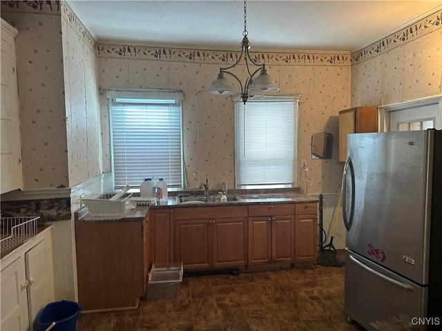 kitchen with stainless steel refrigerator, sink, pendant lighting, and a notable chandelier