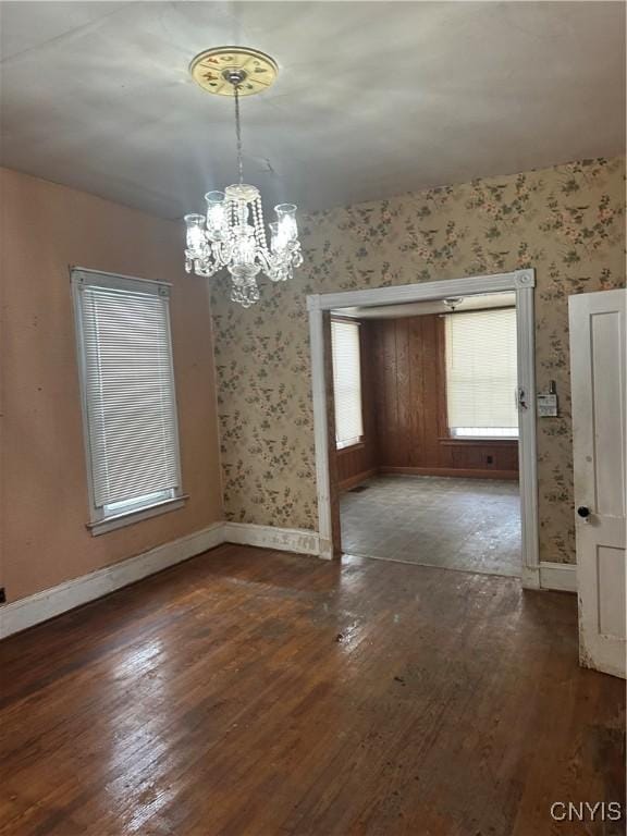 unfurnished dining area featuring dark wood-type flooring and a notable chandelier