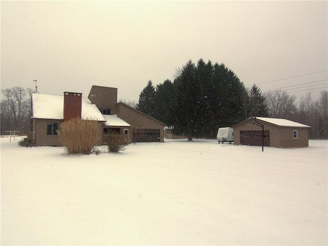 yard layered in snow with a garage and an outdoor structure