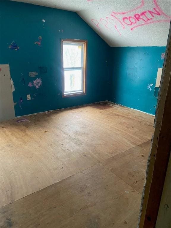 unfurnished bedroom with a textured ceiling and vaulted ceiling