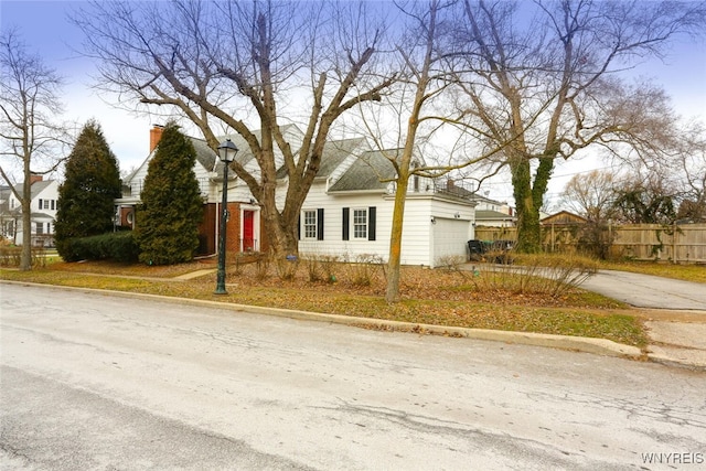 view of front facade with concrete driveway, an attached garage, and fence