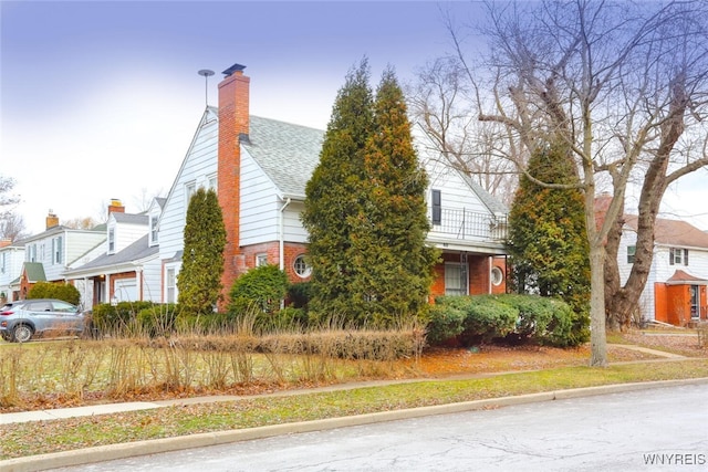 view of side of property with brick siding, a chimney, and a shingled roof