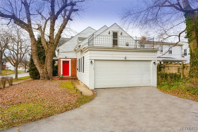 view of front of property featuring a garage, fence, a balcony, and aphalt driveway