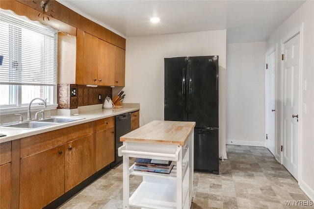 kitchen with baseboards, butcher block countertops, brown cabinets, black appliances, and a sink