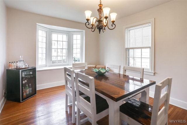 dining room featuring wine cooler, an inviting chandelier, baseboards, and wood finished floors