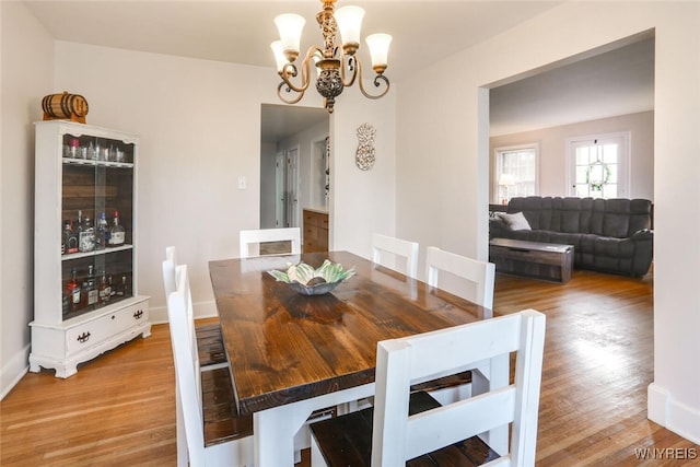 dining room with baseboards, an inviting chandelier, and wood finished floors