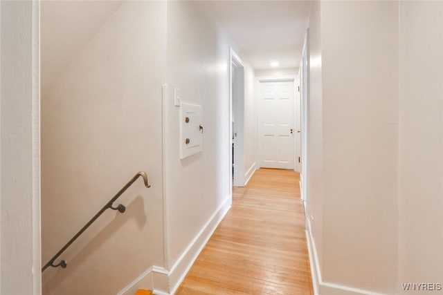 corridor with light wood-type flooring, baseboards, and an upstairs landing