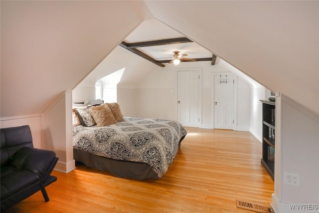 bedroom with ceiling fan, visible vents, vaulted ceiling with beams, and wood finished floors