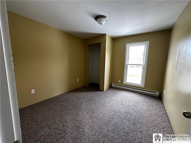 carpeted empty room with a baseboard heating unit