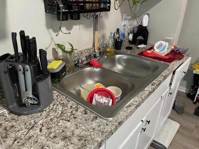 details featuring light stone countertops, sink, and white cabinets