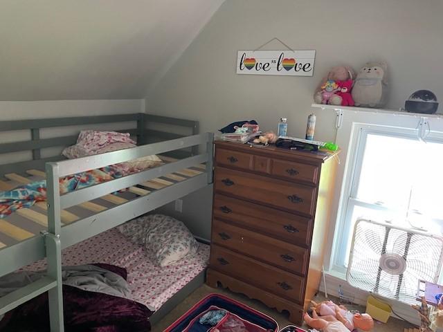 bedroom with vaulted ceiling and multiple windows