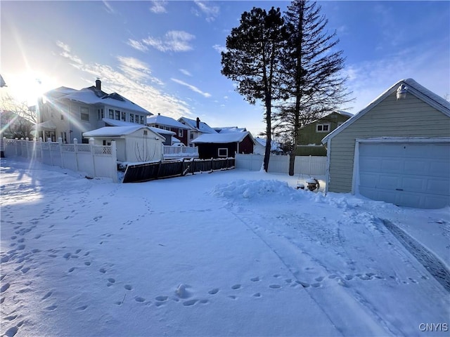 yard covered in snow featuring a garage and an outbuilding