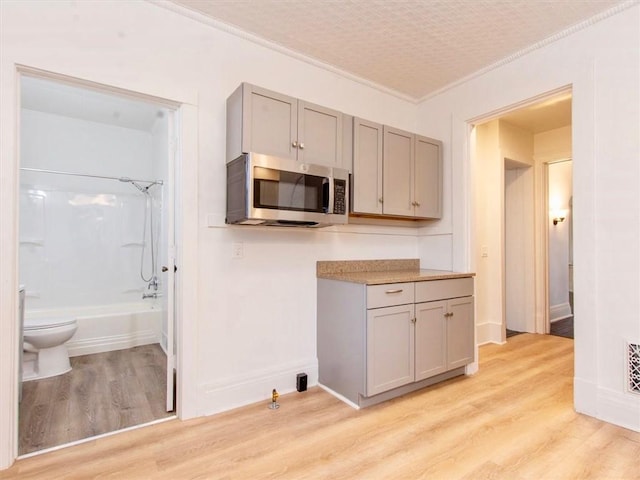 kitchen featuring ornamental molding, light hardwood / wood-style floors, and gray cabinetry