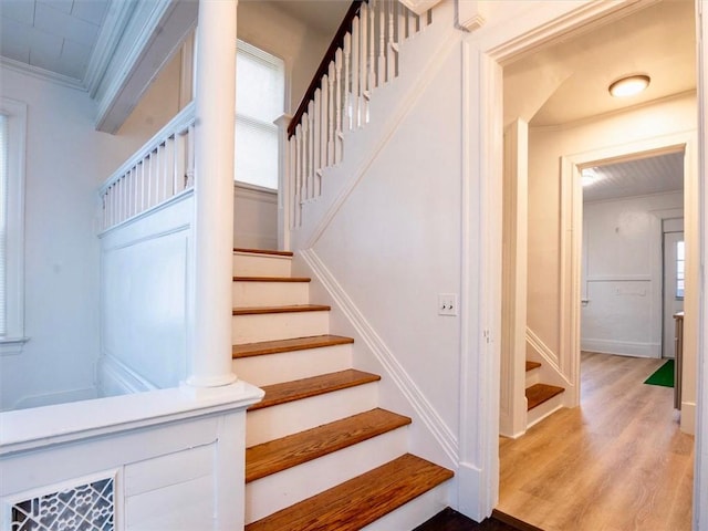 staircase featuring a wealth of natural light, wood-type flooring, and ornamental molding