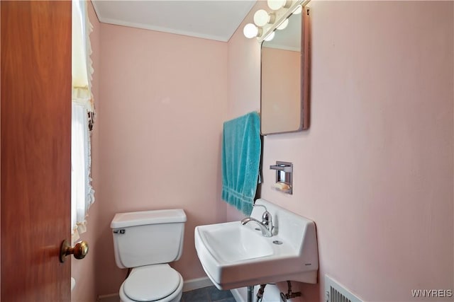 bathroom featuring toilet, ornamental molding, and sink