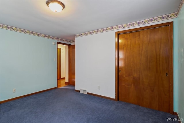 unfurnished bedroom with a closet and dark colored carpet