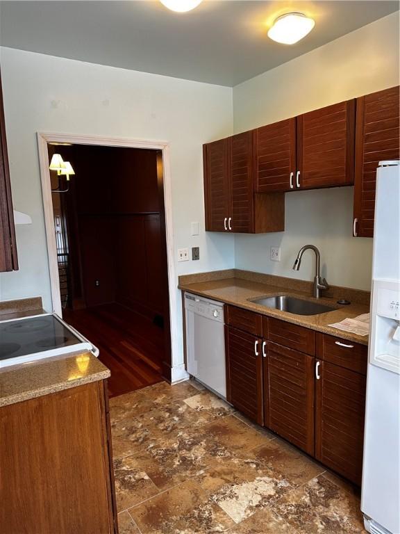 kitchen with light stone countertops, sink, and white appliances