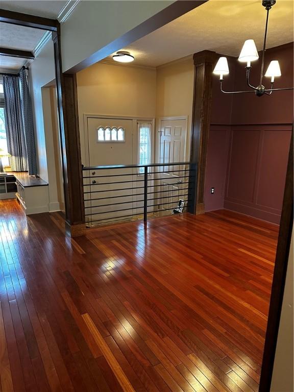 foyer entrance featuring dark hardwood / wood-style floors, an inviting chandelier, and ornamental molding