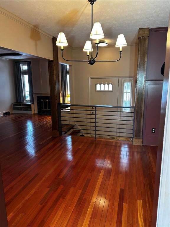 interior space featuring crown molding, wood-type flooring, and a textured ceiling