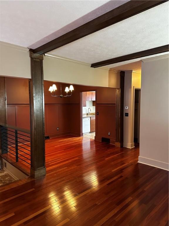 unfurnished living room with dark hardwood / wood-style flooring, beamed ceiling, a textured ceiling, and sink