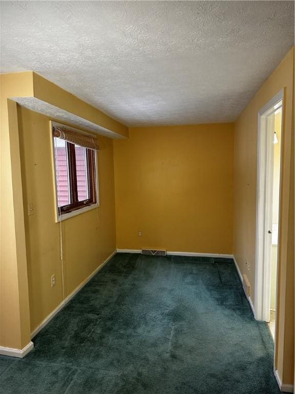 unfurnished room with a textured ceiling and dark carpet