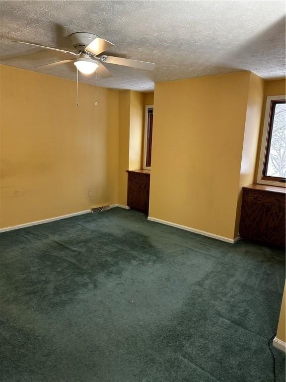 spare room with dark colored carpet, a textured ceiling, and ceiling fan