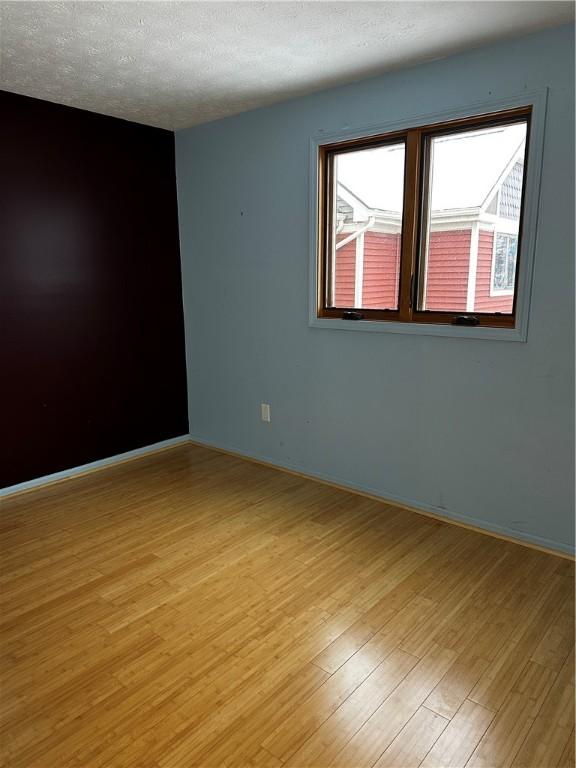 unfurnished room featuring a textured ceiling and light hardwood / wood-style floors