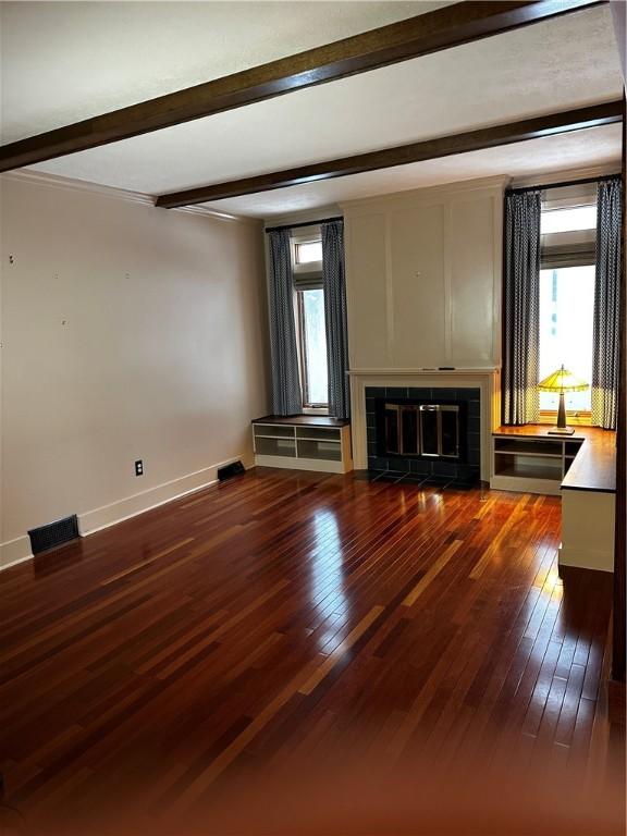 unfurnished living room with a fireplace, beamed ceiling, and dark hardwood / wood-style floors