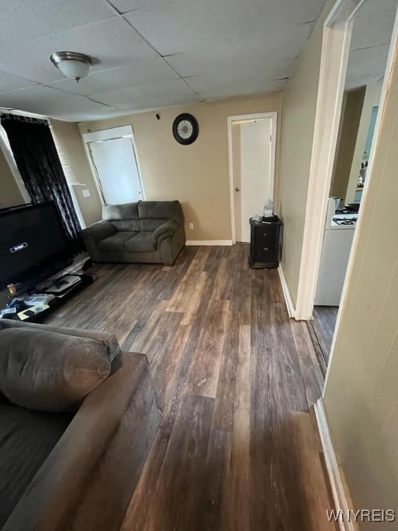 living room featuring dark wood-type flooring and a drop ceiling