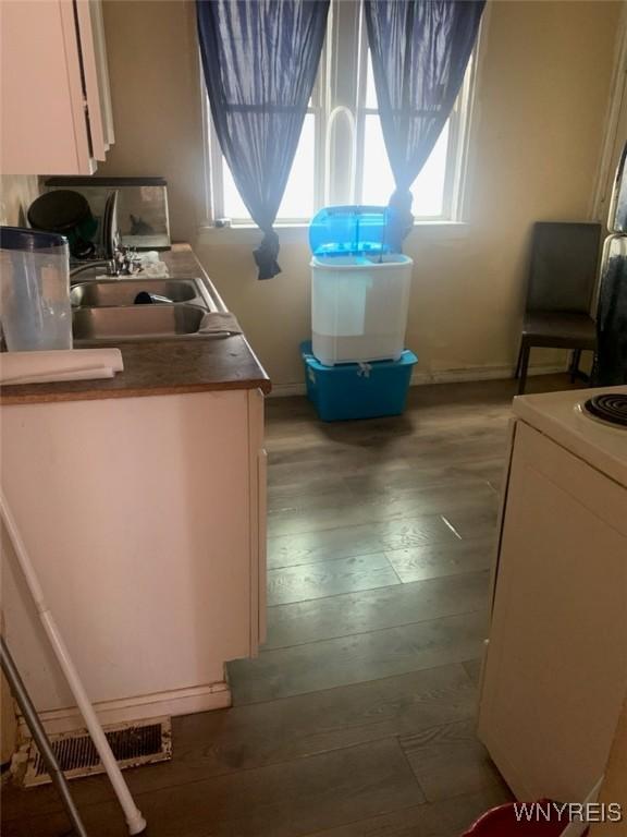 kitchen with white cabinetry, wood-type flooring, range, and sink