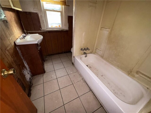 bathroom with vanity, tile patterned floors, wooden walls, a washtub, and toilet