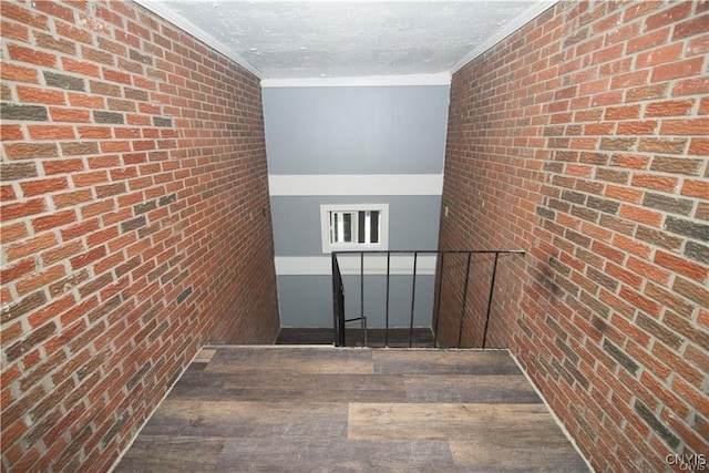 interior space with crown molding and brick wall