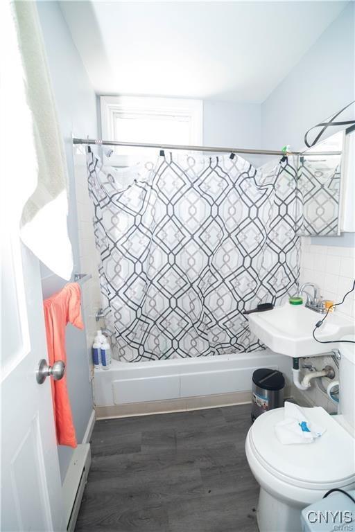 bathroom featuring hardwood / wood-style floors, sink, a shower with shower curtain, toilet, and baseboard heating