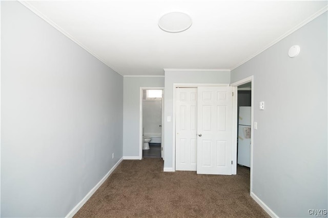 unfurnished bedroom with dark colored carpet, white refrigerator, crown molding, connected bathroom, and a closet