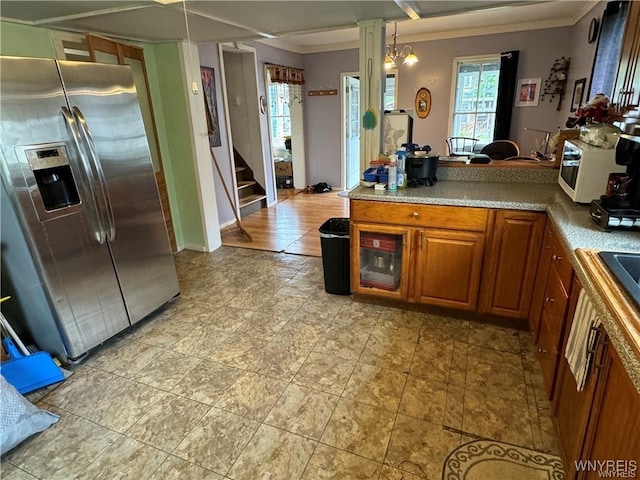 kitchen featuring crown molding, pendant lighting, stainless steel refrigerator with ice dispenser, and a notable chandelier