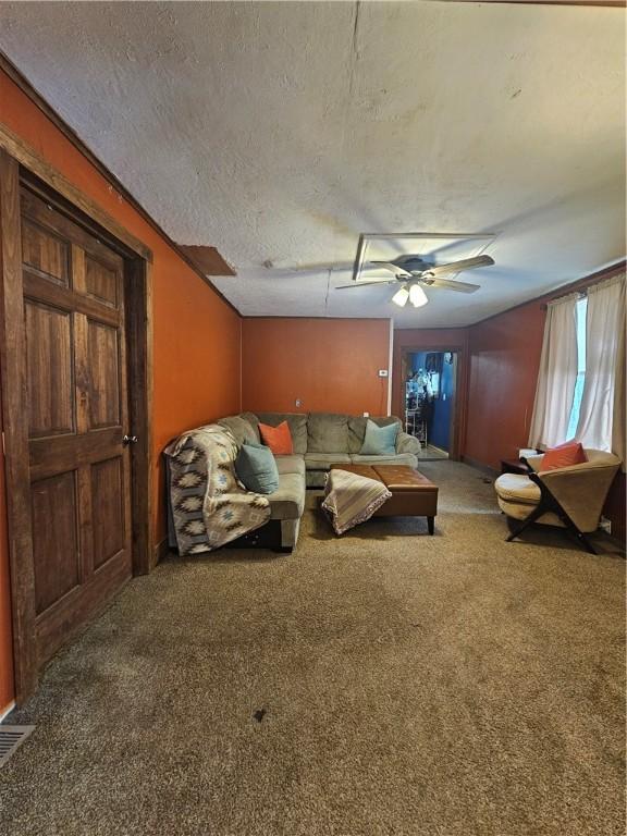 living room featuring ceiling fan, carpet floors, and a textured ceiling