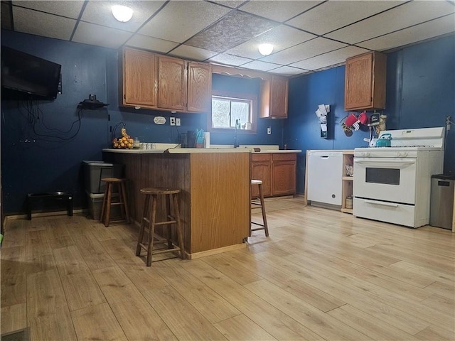 kitchen with a breakfast bar, white appliances, kitchen peninsula, and light hardwood / wood-style floors