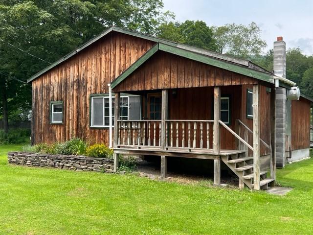 rear view of property featuring a porch and a lawn