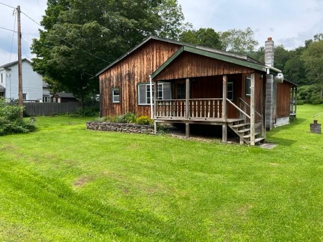 rear view of property featuring a yard and covered porch