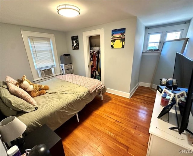 bedroom with hardwood / wood-style floors, a spacious closet, a closet, and cooling unit